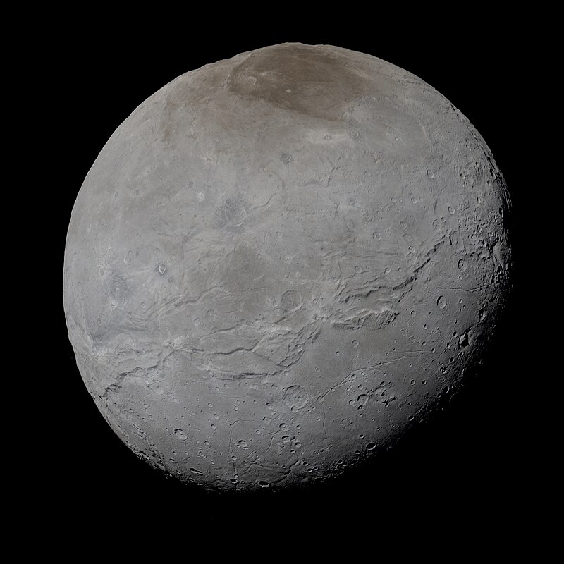 En bild av Charon, Plutos måne. Ett runt, vitt och stenigt objekt.