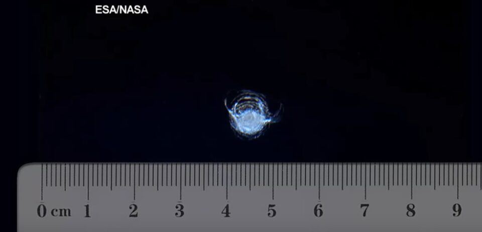 En linjal som visar proportionerna av skadan på fönstret på ISS.